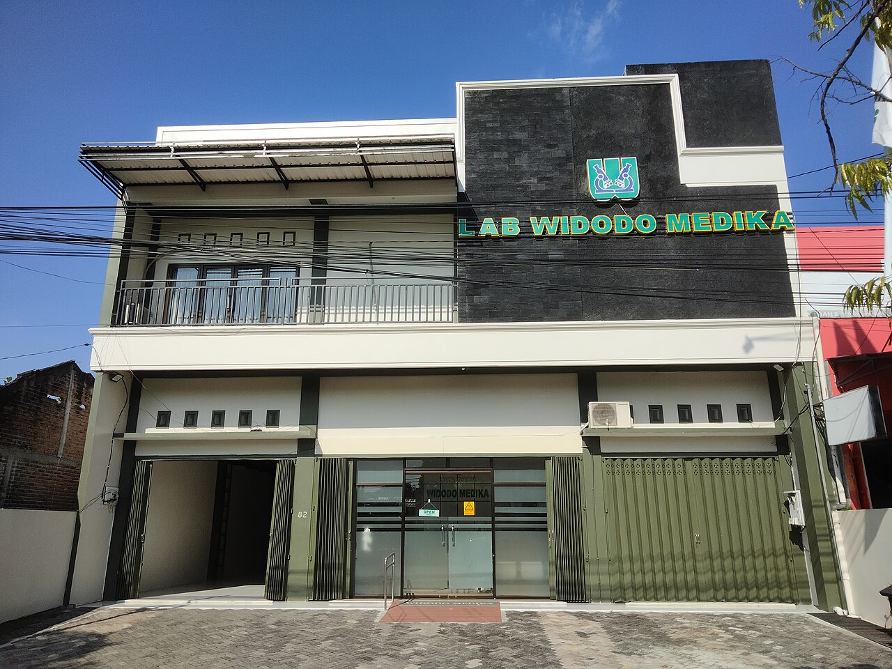 Gedung laboratorium klinik dengan papan nama di tepi jalan